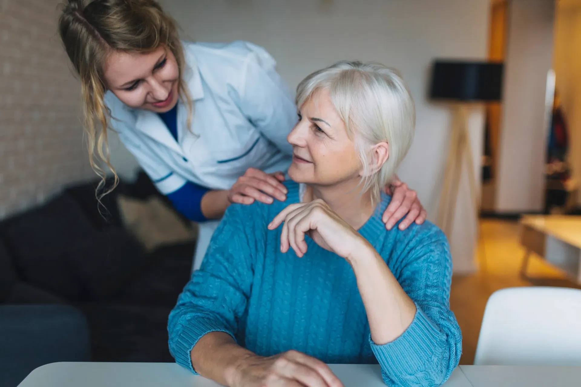 A caregiver offers friendly support to an older adult at home